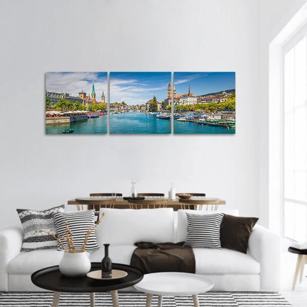 Lake Zurich Riverfront with Grossmünster Towers Panoramic Canvas Wall Art in white, green and blue, hung on a wall