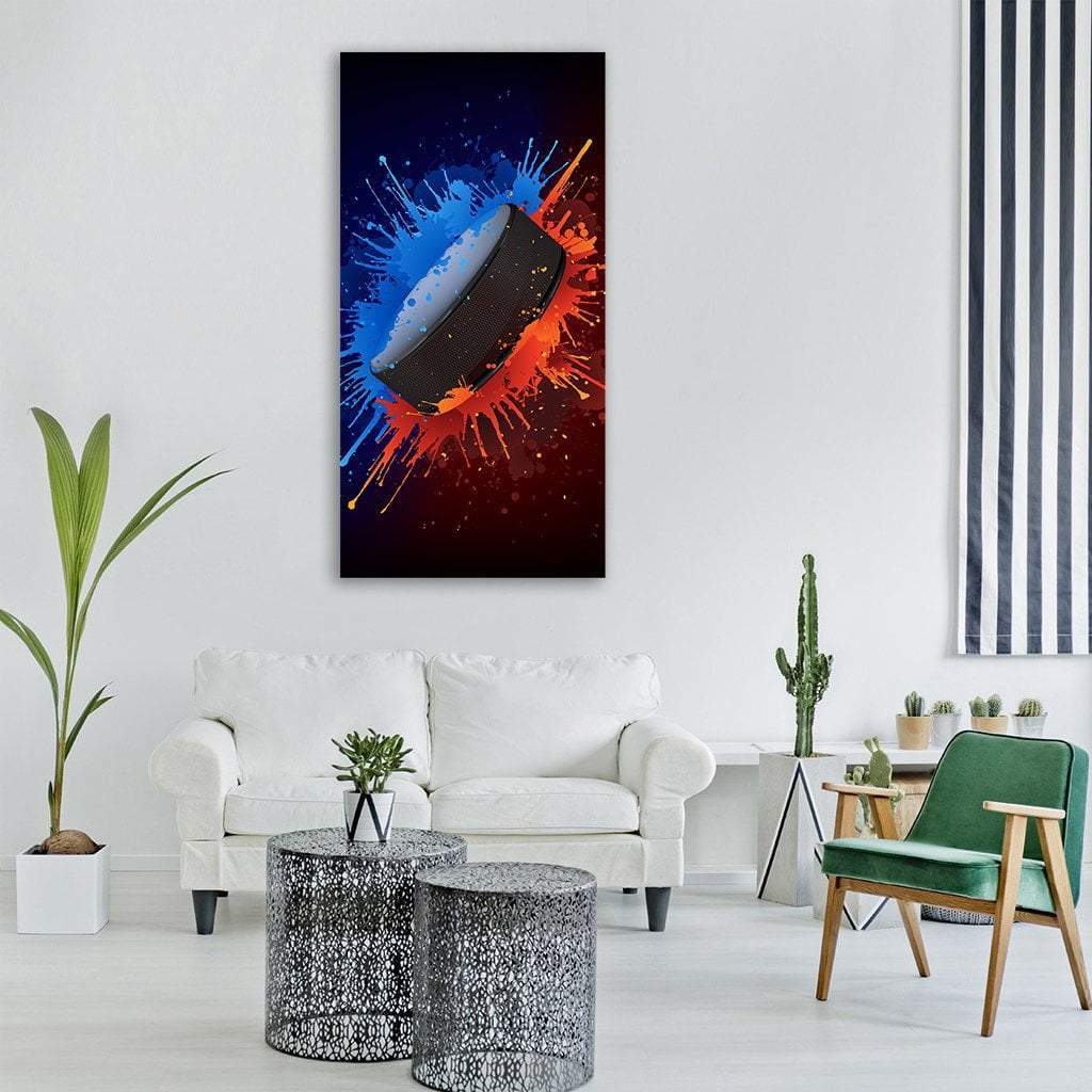 Hockey Puck with Paint Splashes Vertical Canvas Wall Art in black, orange and blue, hung on a wall