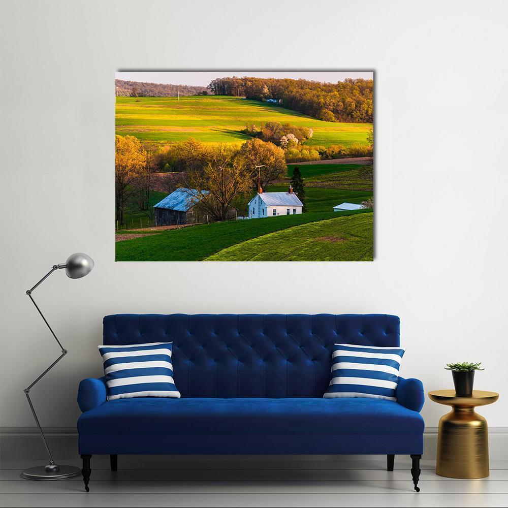 White Farmhouse and Weathered Barn at Golden Hour Canvas Wall Art in gold, yellow and green, single panel hung on a wall