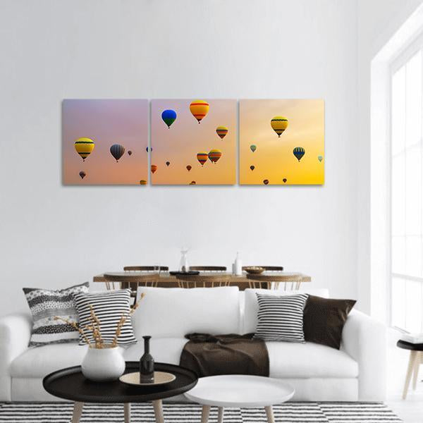Hot Air Balloons Over Gradient Sky Panoramic Canvas Wall Art in orange, yellow and purple, hung on a wall