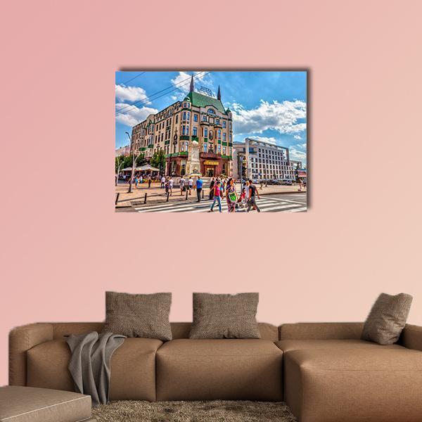 Hotel with Green Pointed Roof on Busy Street Canvas Wall Art in beige, green and blue, single panel hung on a wall