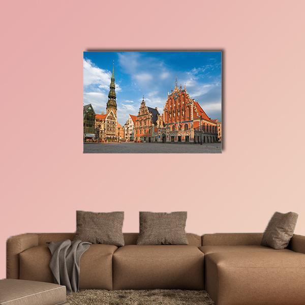 House of the Blackheads, Sunny Town Square Canvas Wall Art in brown, orange and blue, single panel hung on a wall
