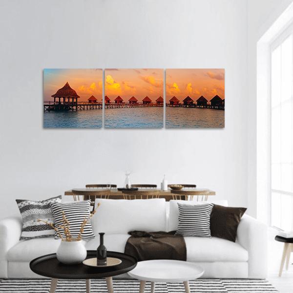 Overwater Bungalows at Sunset Panoramic Canvas Wall Art in orange, yellow and blue, hung on a wall