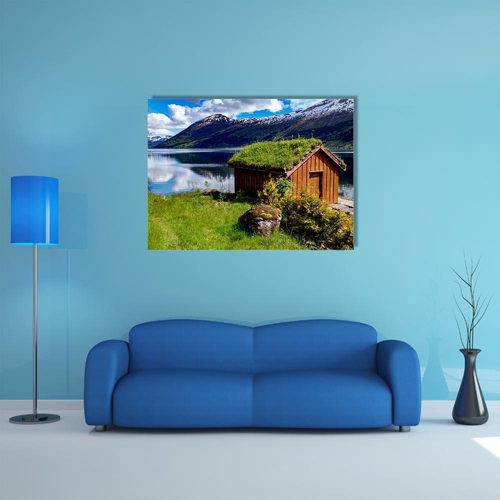 Norwegian Lakeside Hut with Sod Roof Canvas Wall Art in brown, green and blue, single panel hung on a wall