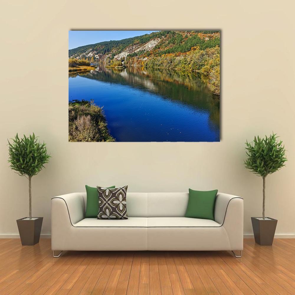 Autumn River Reflections with Rocky Hills Canvas Wall Art in orange, green and blue, single panel hung on a wall