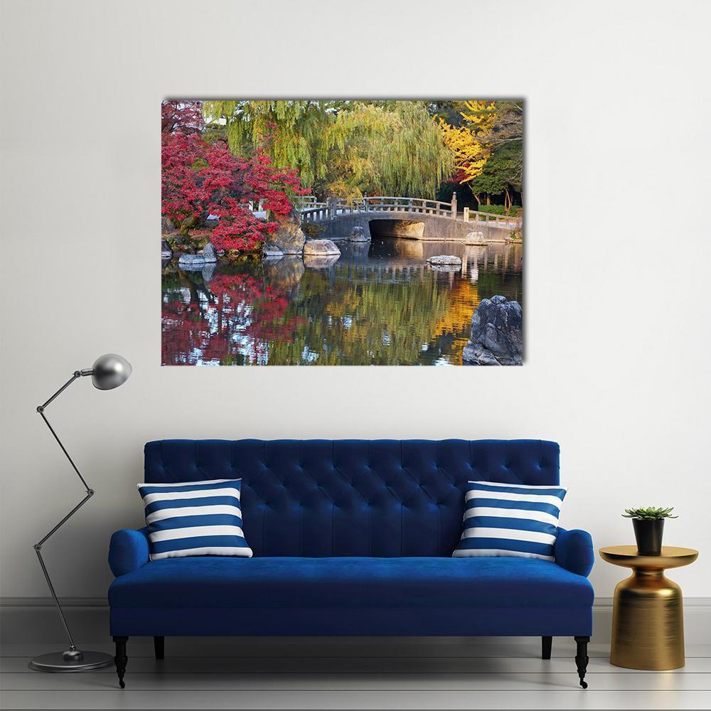 Japanese Pond with Arched Stone Bridge Canvas Wall Art in red, yellow and green, single panel hung on a wall