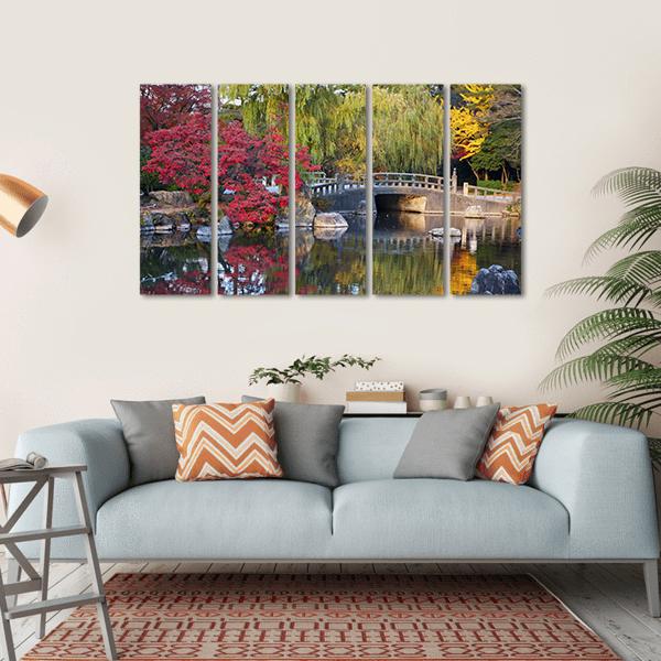 Japanese Pond with Arched Stone Bridge Canvas Wall Art in red, yellow and green, hung on a wall