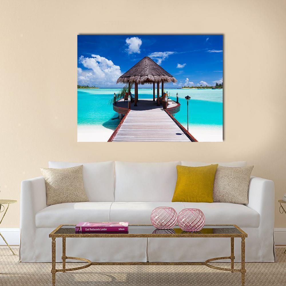 Thatched Jetty Over Turquoise Ocean Canvas Wall Art in white, brown and blue, single panel hung on a wall
