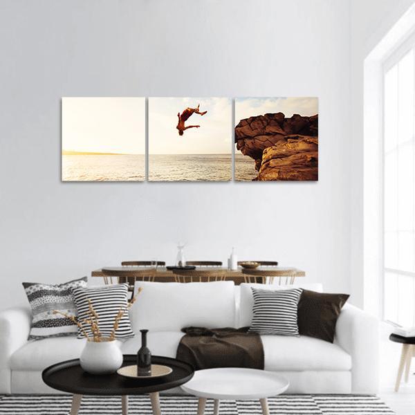 Cliff Diver Over Ocean at Sunset Panoramic Canvas Wall Art in brown, orange and yellow, hung on a wall