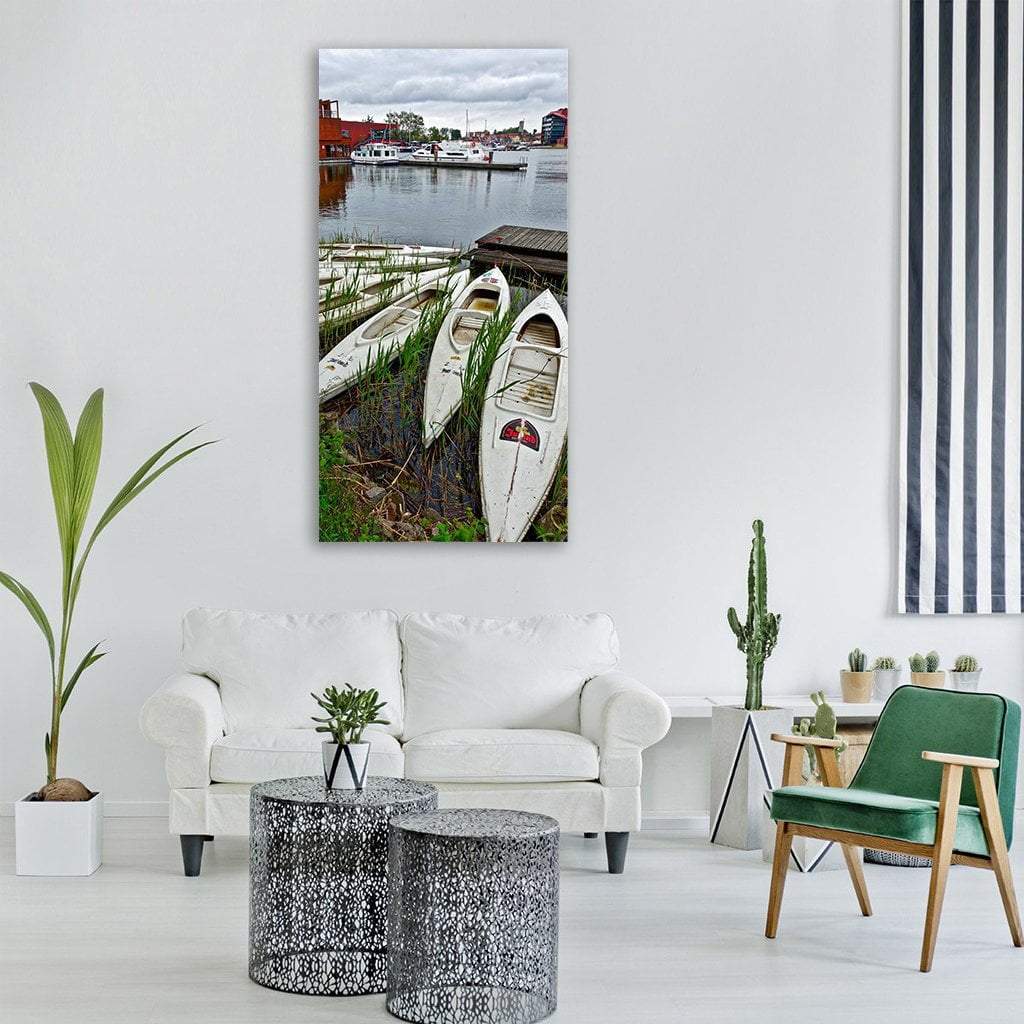 White Canoes at a Quiet Harbor Vertical Canvas Wall Art in white, gray and green, single vertical panel hung on a wall