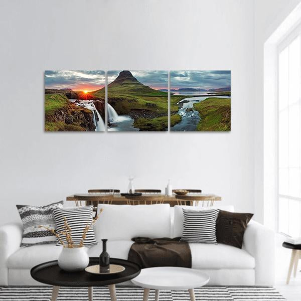 Kirkjufell Mountain and Kirkjufellsfoss at Sunset Panoramic Canvas Wall Art in orange, green and blue, hung on a wall