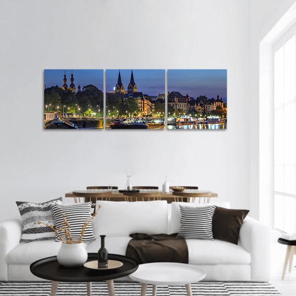Koblenz Riverfront Skyline at Twilight Panoramic Canvas Wall Art in yellow, blue and navy, hung on a wall