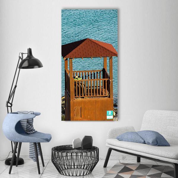 Watchtower in Konnos Bay Vertical Canvas Wall Art in brown and blue, single vertical panel hung on a wall