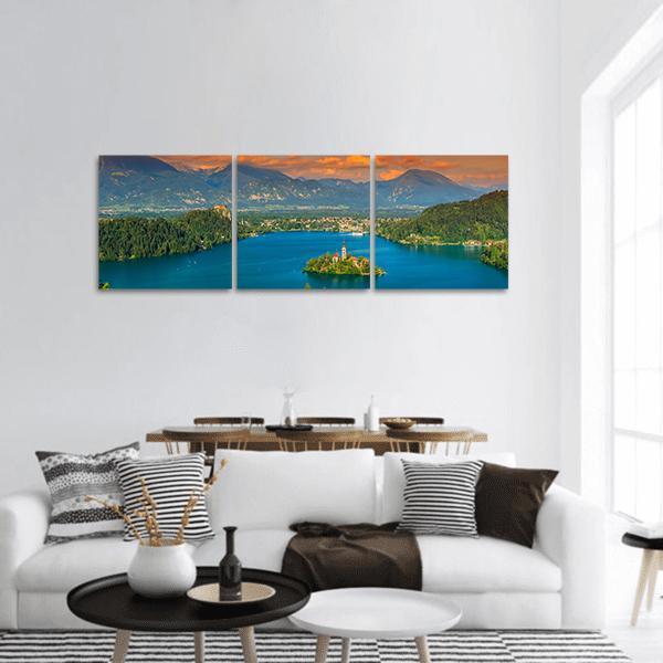St Mary's Church on Lake Bled Panoramic Canvas Wall Art in orange, green and blue, hung on a wall