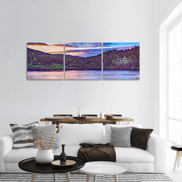 Sunset Lake with Cabins Panoramic Canvas Wall Art in orange, blue and purple, hung on a wall
