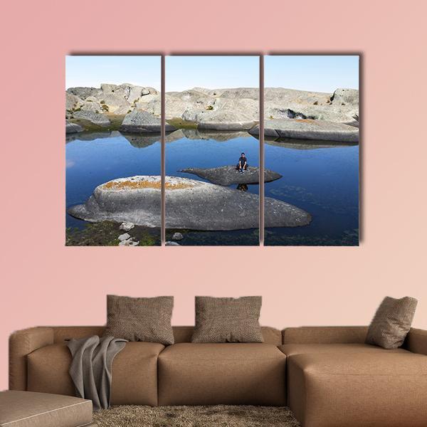 Marcahuasi Lake with Figure on Rock Canvas Wall Art in gray, brown and blue, hung on a wall