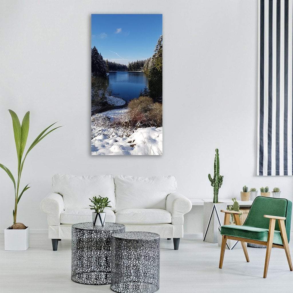 Snow-covered Lake Shore with Evergreens Vertical Canvas Wall Art in white, green and blue, single vertical panel hung on a wall