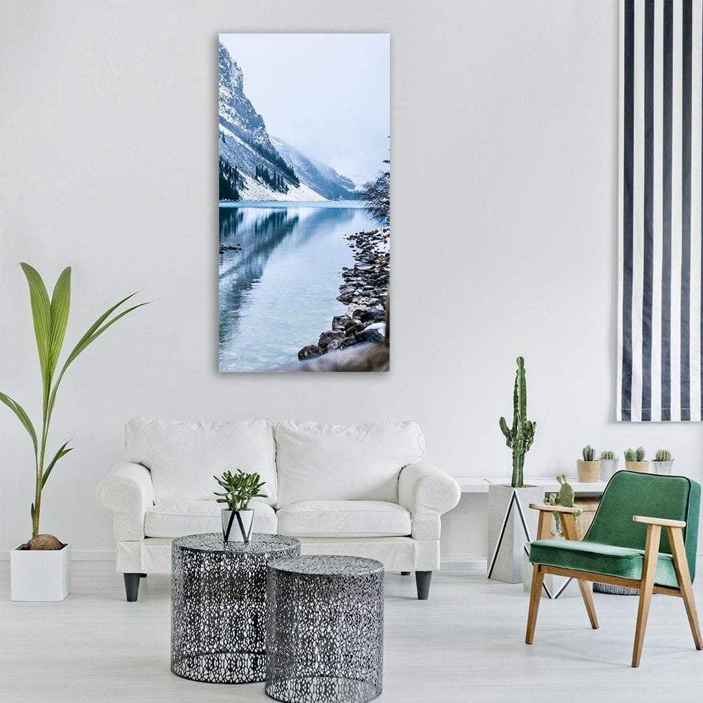 Snow-dusted Mountain Reflected in Lake Vertical Canvas Wall Art in white, gray and blue, single vertical panel hung on a wall
