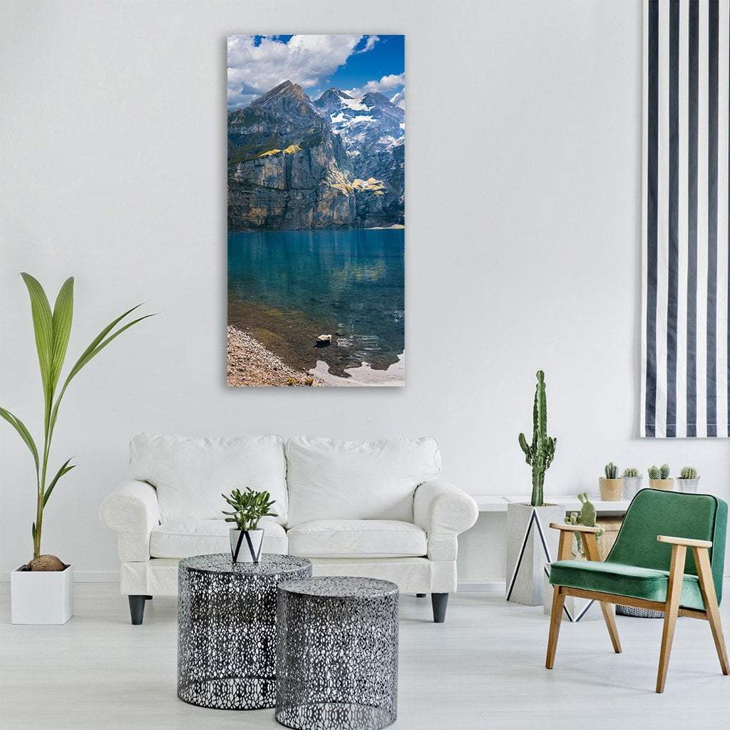 Turquoise Alpine Lake with Mountain Reflections Vertical Canvas Wall Art in gray and blue, single vertical panel hung on a wall