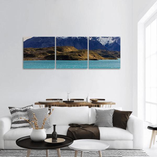Turquoise Alpine Lake with Snow Peaks Panoramic Canvas Wall Art in white, brown and blue, hung on a wall