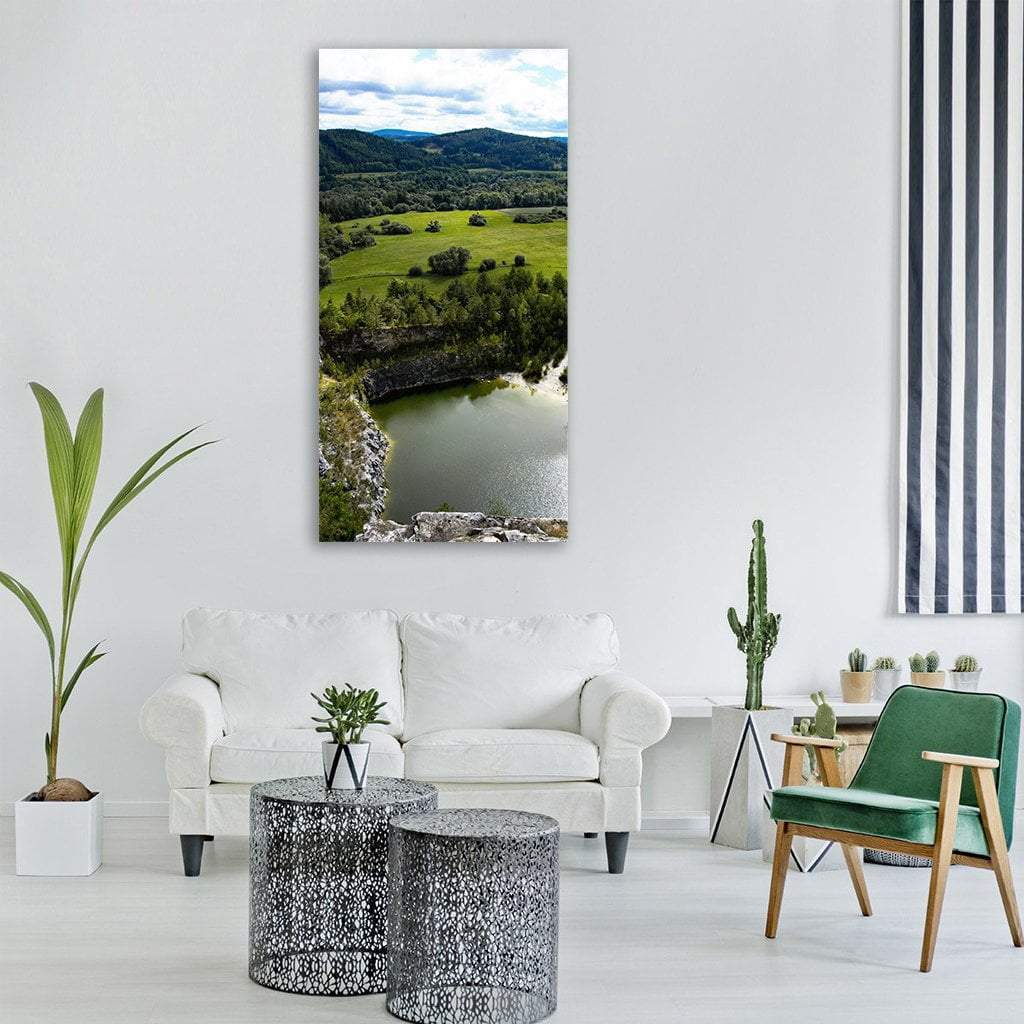 Clifftop View of Quarry Lake Vertical Canvas Wall Art in gray, green and blue, single vertical panel hung on a wall