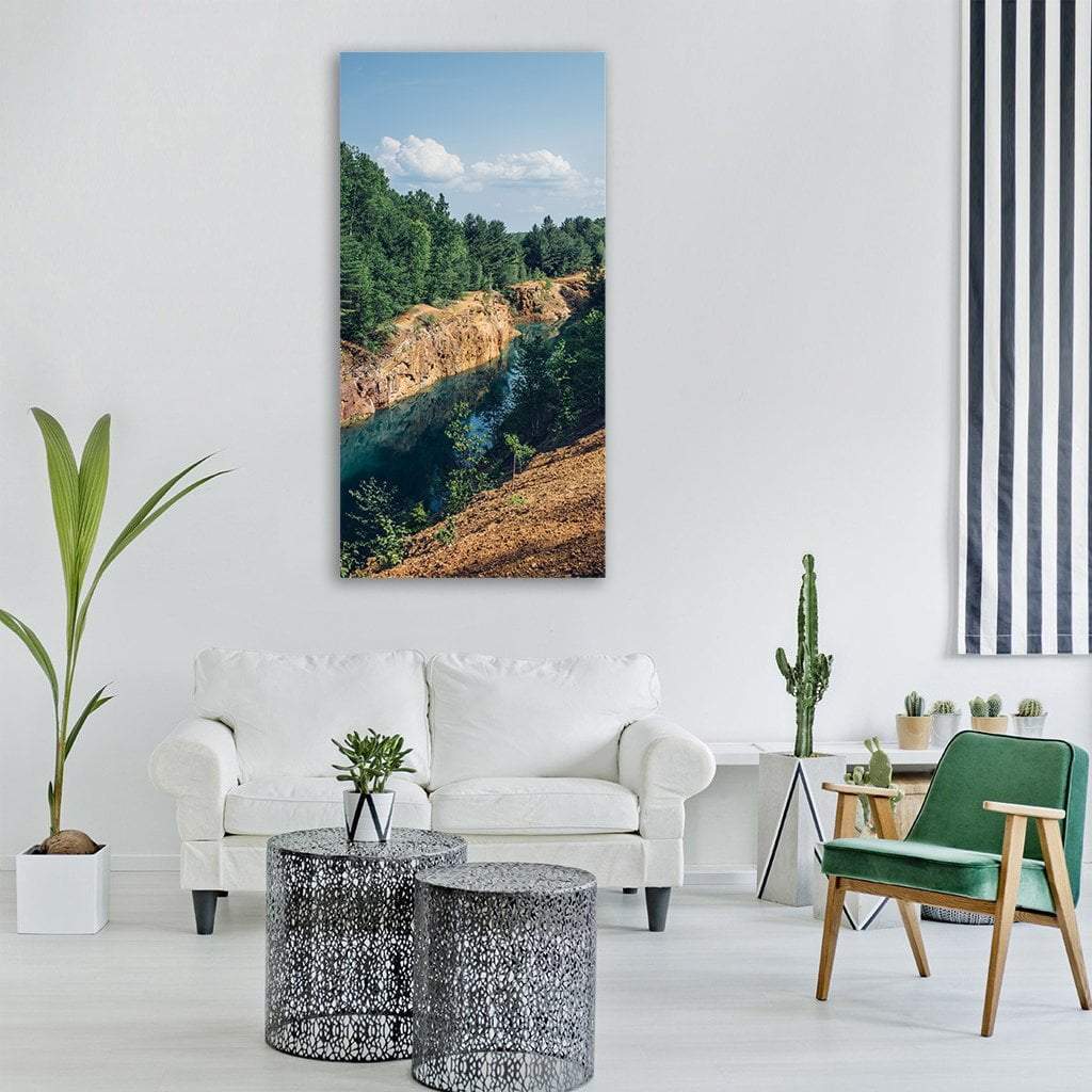 Turquoise Quarry Lake Amid Green Trees Vertical Canvas Wall Art in brown, green and blue, single vertical panel hung on a wall