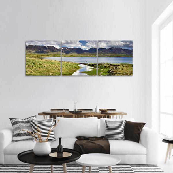 Lake Valley with Snow-capped Mountain Reflections Panoramic Canvas Wall Art in white, green and blue, hung on a wall