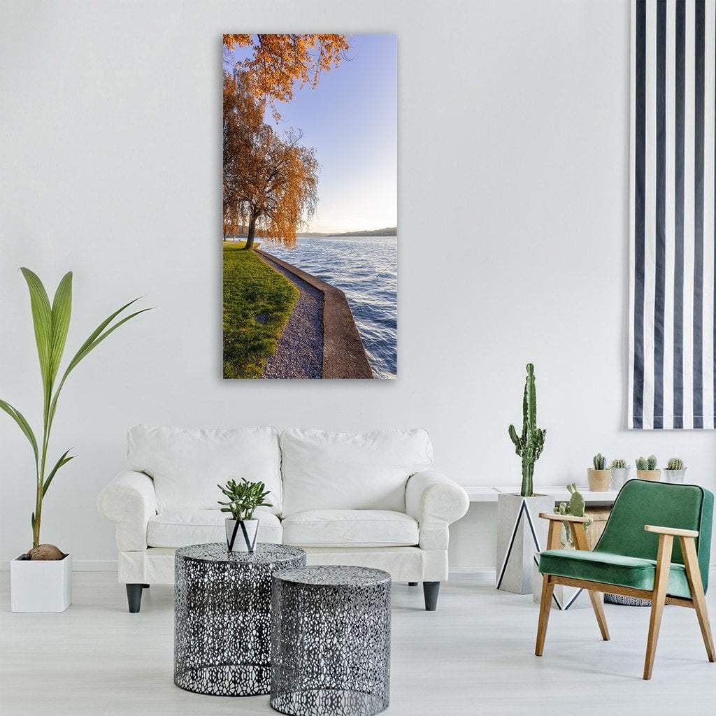 Lake with Autumn Meadow Vertical Canvas Wall Art in orange, green and blue, single vertical panel hung on a wall