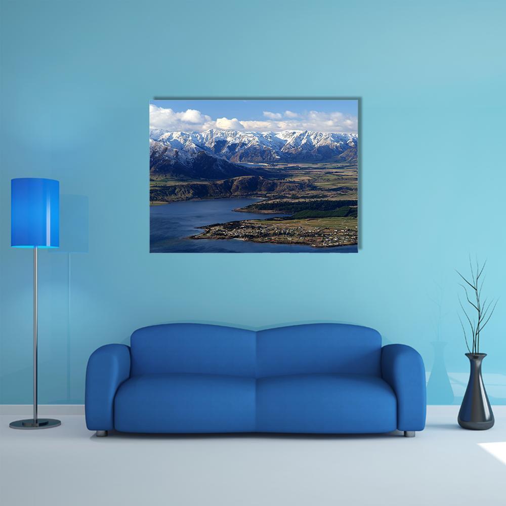 Snow-capped Mountain Over Lakeside Town Canvas Wall Art in white, brown and blue, single panel hung on a wall