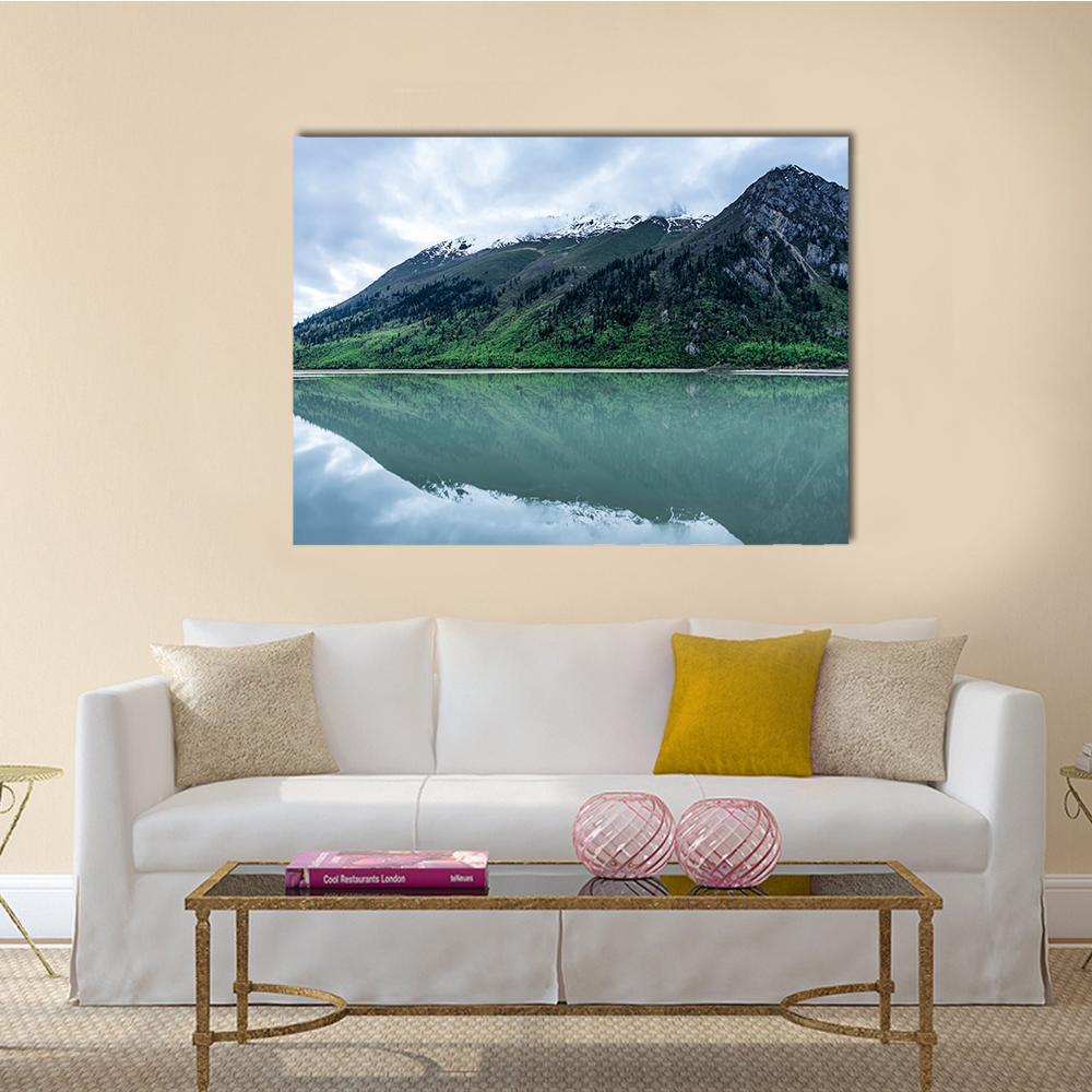 Mountain Lake Reflection with Snow-capped Peaks Canvas Wall Art in gray, green and blue, single panel hung on a wall
