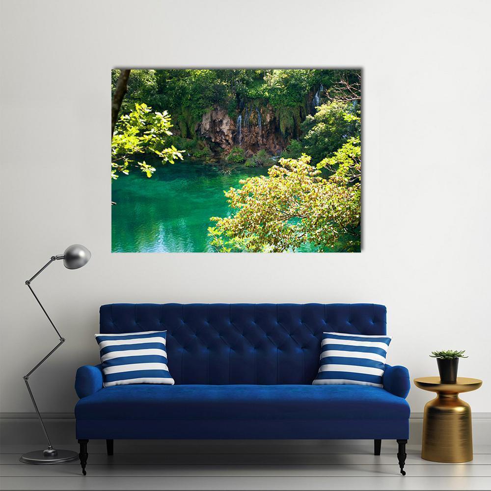 Emerald Forest Lake Canvas Wall Art in brown and green, single panel hung on a wall
