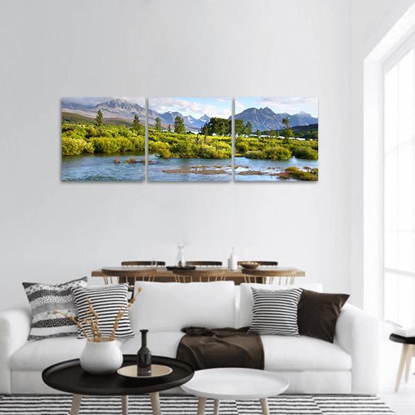 Lake with Snow-capped Peaks and Lush Riverbank Panoramic Canvas Wall Art in gray, green and blue, hung on a wall