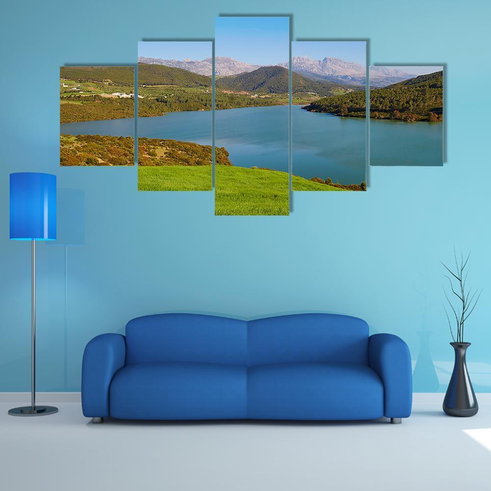 Serene Lake Among Rolling Green Hills Canvas Wall Art in green and blue, 5 panel Star layout hung on a wall