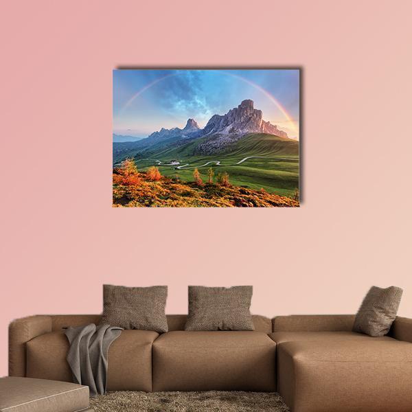 Alpine Rainbow Over Winding Mountain Road Canvas Wall Art in orange, green and blue, single panel hung on a wall