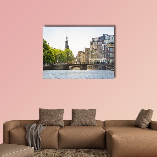 Amsterdam Canal with Spired Tower Canvas Wall Art in brown, green and blue, single panel hung on a wall