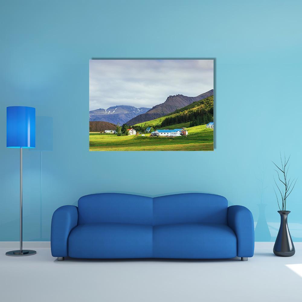 Farmhouses Below Snow-capped Mountains Canvas Wall Art in white, green and blue, single panel hung on a wall