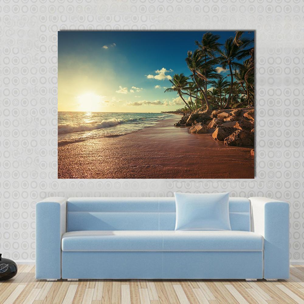 Golden Sunrise Beach with Palm Trees and Rocks Canvas Wall Art in gold, yellow and blue, single panel hung on a wall