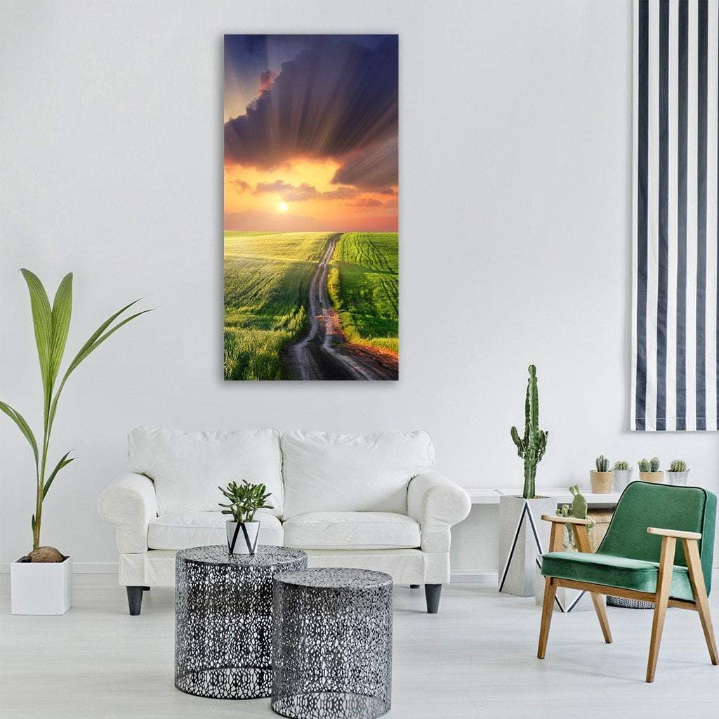 Sunset Country Road Through Rolling Fields Vertical Canvas Wall Art in orange, yellow and green, single vertical panel hung on a wall