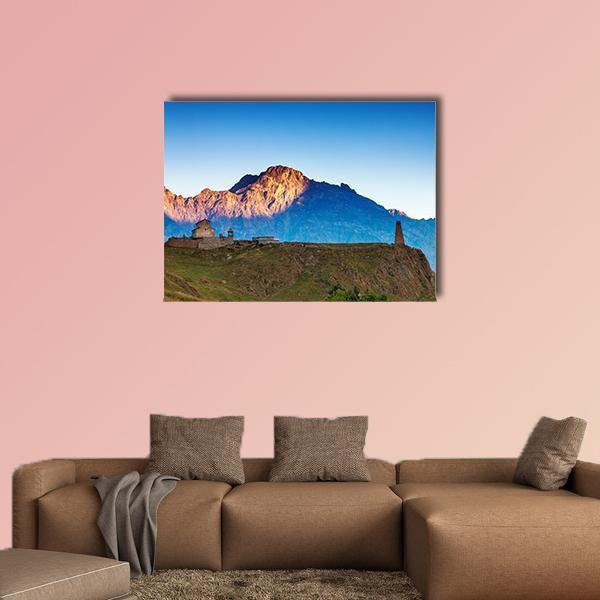 Sunlit Mountain Village with Stone Tower Canvas Wall Art in brown, orange and blue, single panel hung on a wall