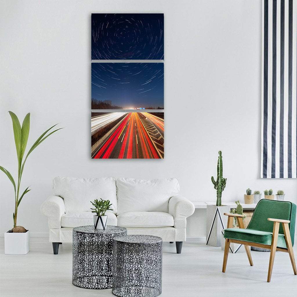 Highway Light Trails Beneath Star Trails Vertical Canvas Wall Art in black, red and blue, hung on a wall