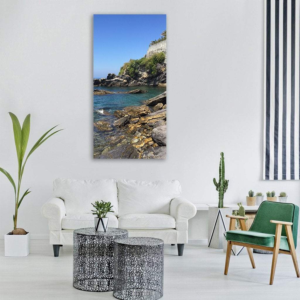 Liguria Rocky Coastline Vertical Canvas Wall Art in gray, brown and blue, single vertical panel hung on a wall