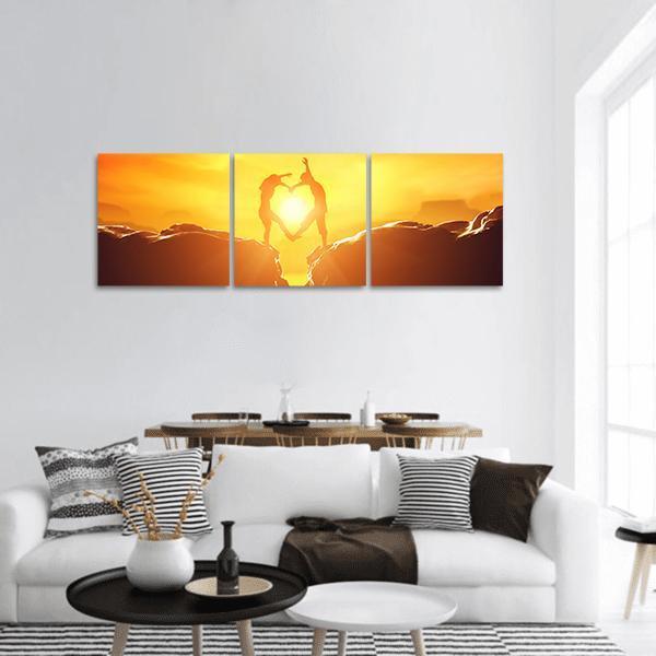 Silhouetted Couple Forming Heart Over Rocky Cliffs Panoramic Canvas Wall Art in brown, orange and yellow, hung on a wall