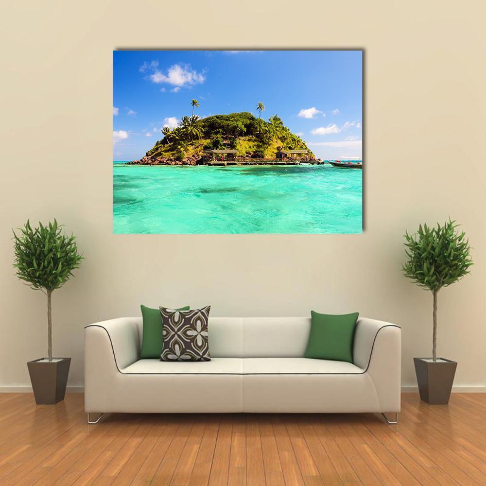 Lush Tropical Island with Overwater Bungalows Canvas Wall Art in white, green and blue, single panel hung on a wall