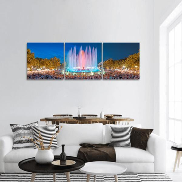 Illuminated Magic Fountain Night Scene Panoramic Canvas Wall Art in orange, yellow and blue, hung on a wall