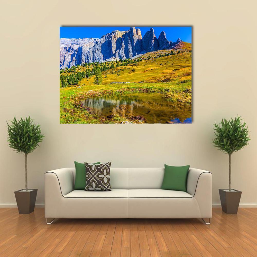 Sunlit Italian Rocky Peaks with Reflecting Pond Canvas Wall Art in yellow, green and blue, single panel hung on a wall