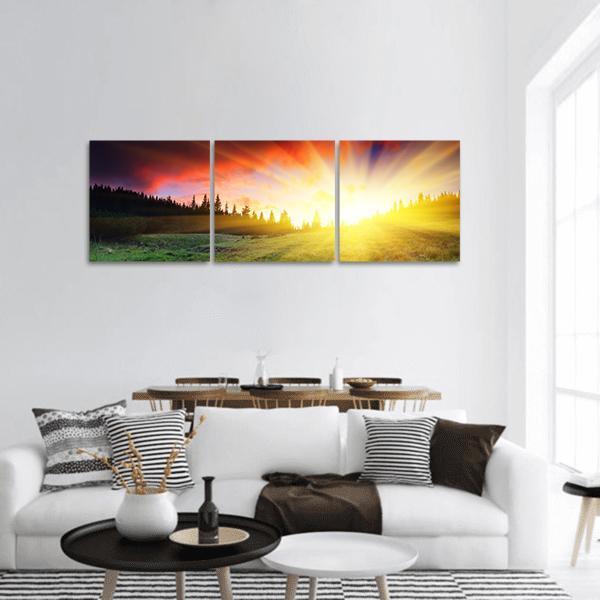 Mountain Sunset with Sunbeams Panoramic Canvas Wall Art in red, orange and yellow, hung on a wall