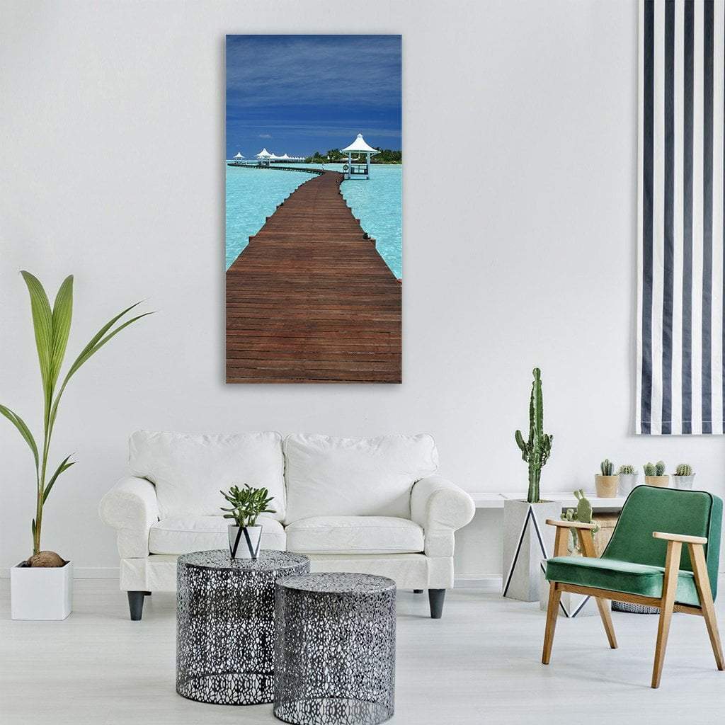 Maldives Pier with White Gazebos Vertical Canvas Wall Art in white, brown and blue, single vertical panel hung on a wall