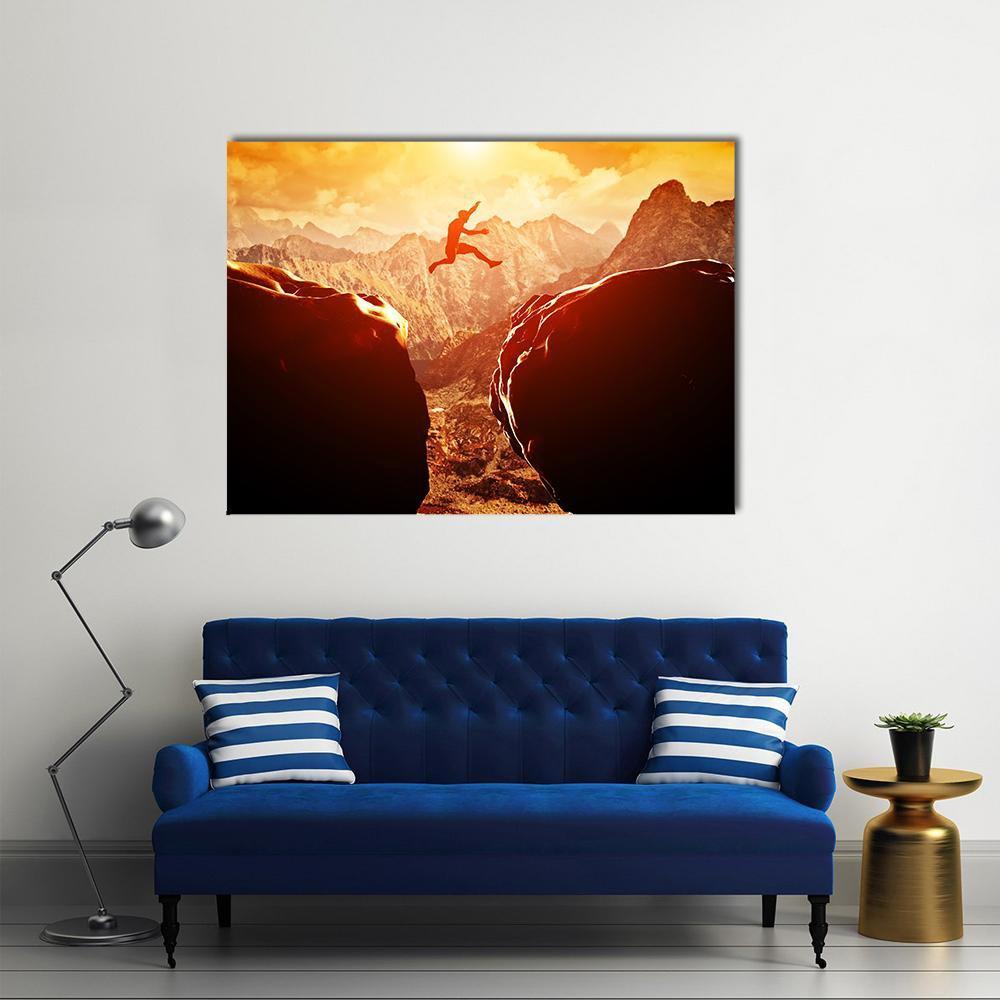 Man Jumping Between Rocks Canvas Wall Art in black, orange and yellow, single panel hung on a wall