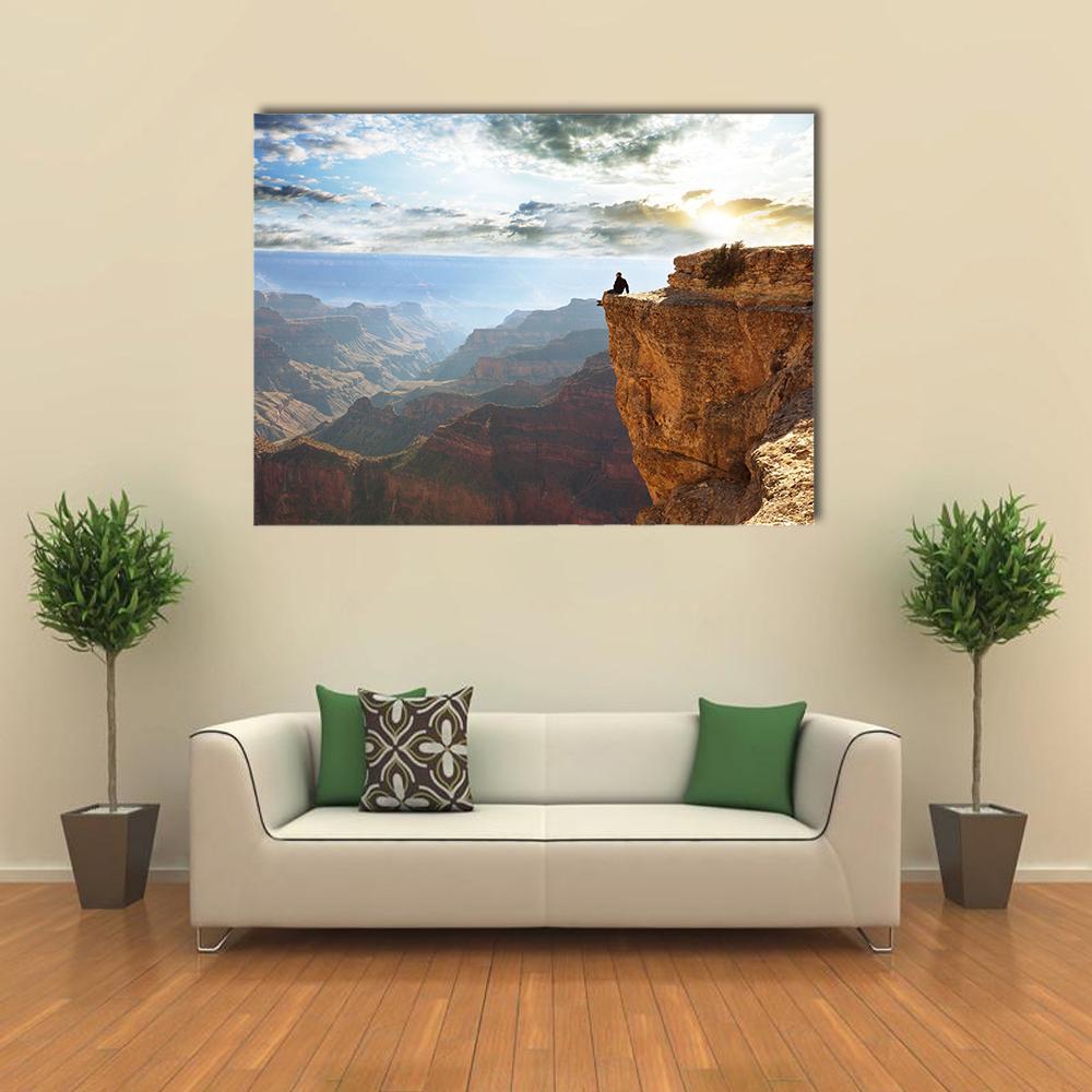 Man Sitting on Grand Canyon Canvas Wall Art in brown, orange and blue, single panel hung on a wall