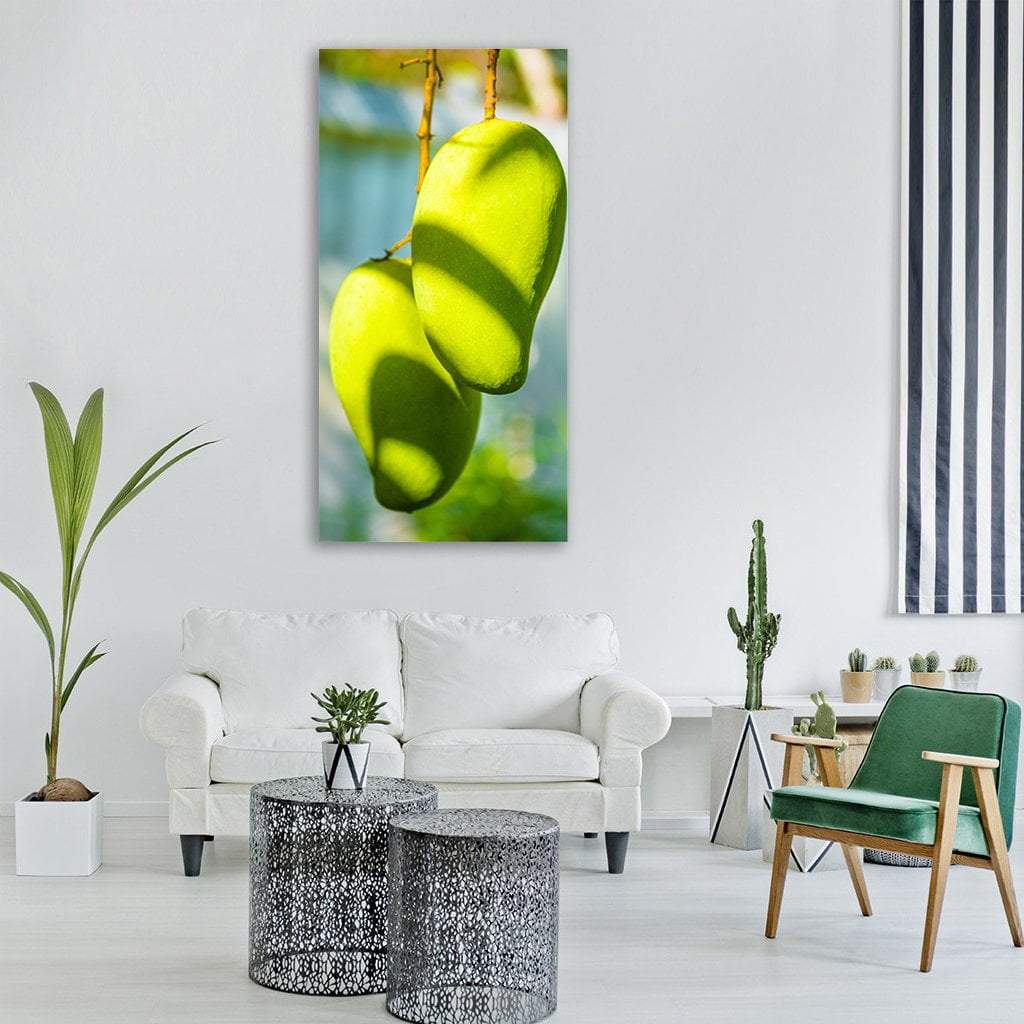 Two Green Mangoes on a Branch Vertical Canvas Wall Art in yellow and green, single vertical panel hung on a wall